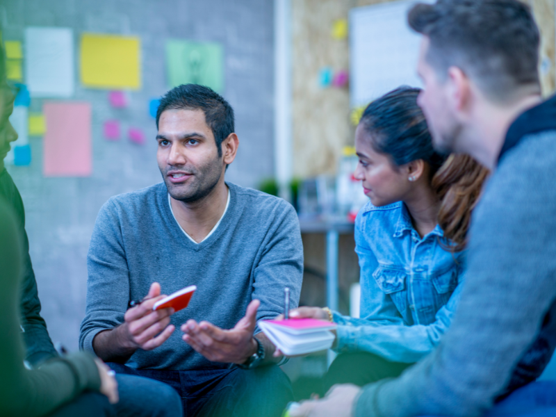 People sit in a circle, speaking in classroom 